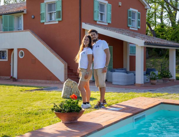 Leonardo e Giulia, host di Villa LeMarche B&B, sorridono accanto alla piscina del giardino.